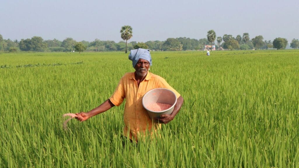 शेतकरी शेतात काम करत असताना MahaDBT Farmer योजनेची माहिती घेत असलेला 